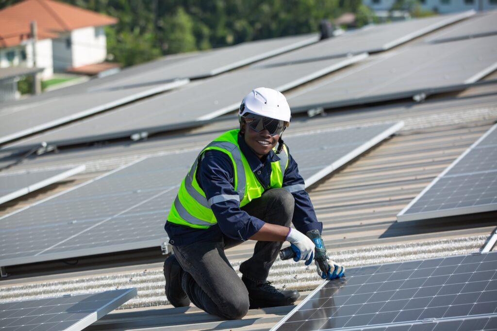 Solar panel installer installing solar panels on roof of warehouse